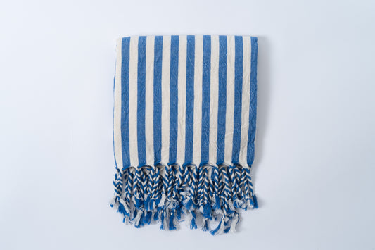 Blue and white striped towel with fringes on a light gray background