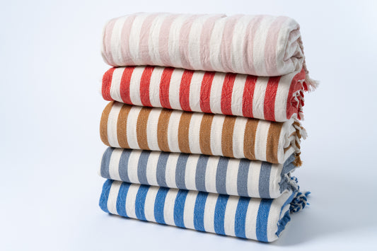 Stack of striped towels in red, white, brown, blue, and gray on a light background
