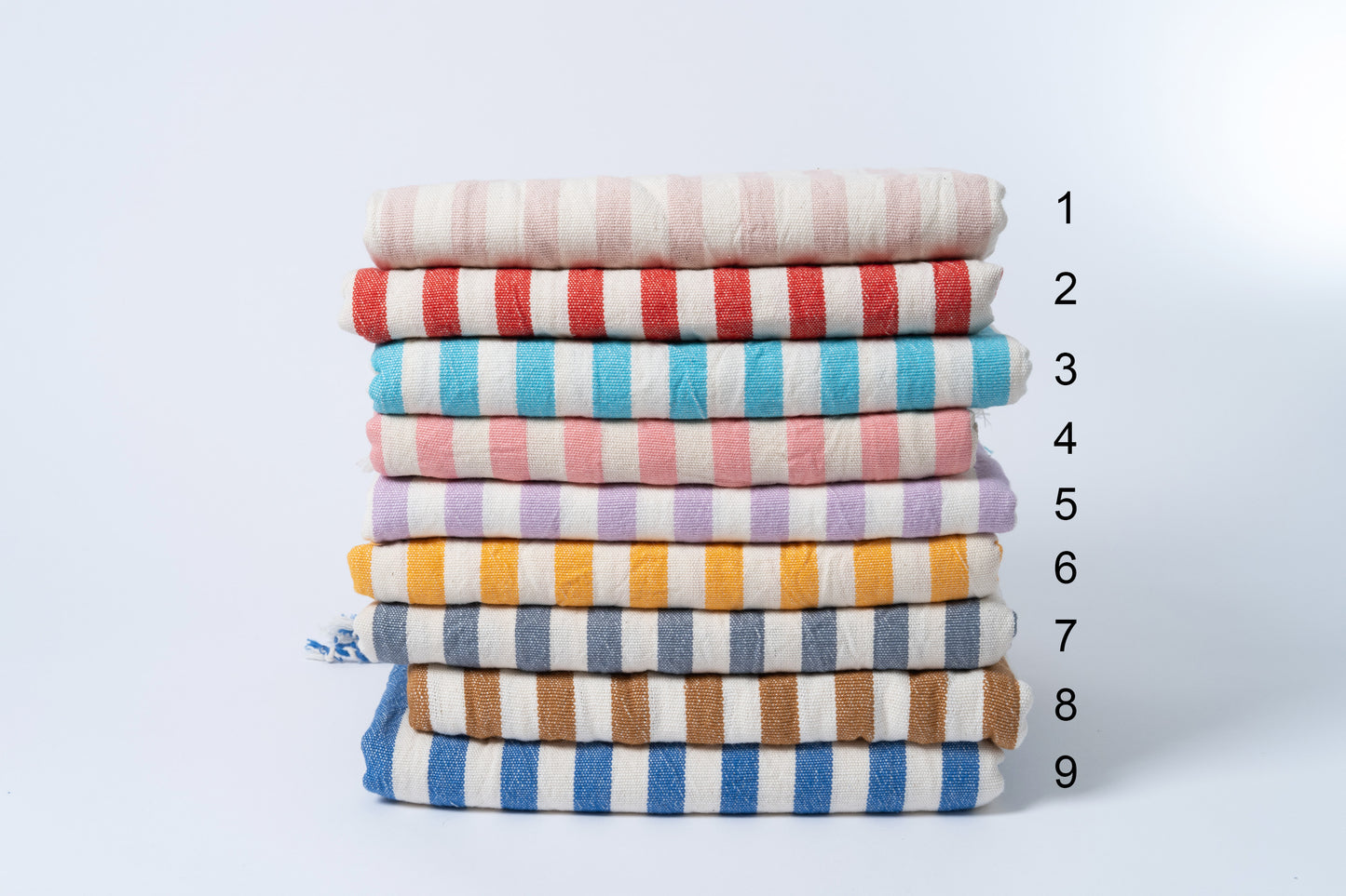 Stack of colorful striped towels with a measurement scale on a light gray background