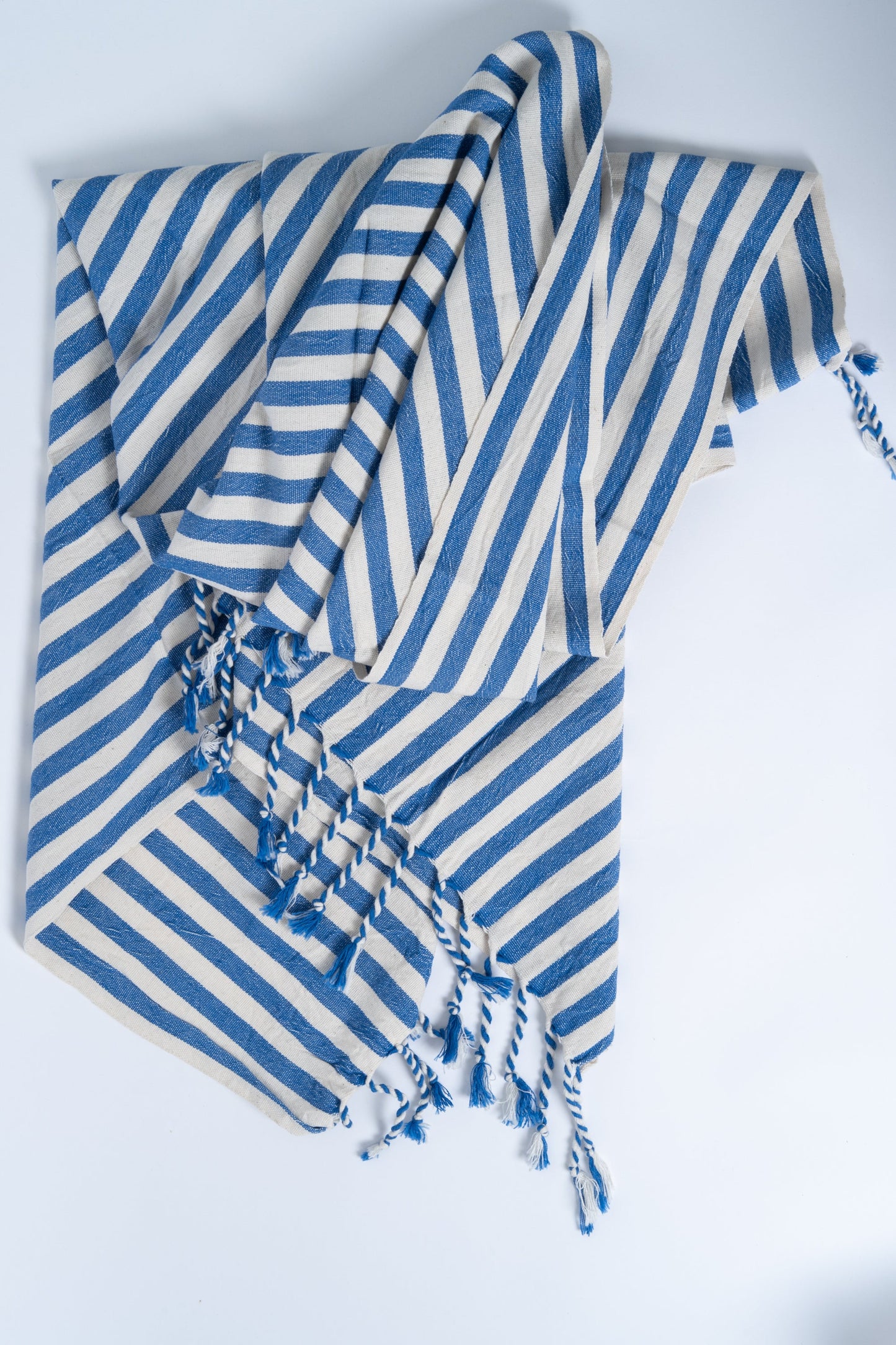 Blue and white striped towel with tassels on a light gray background