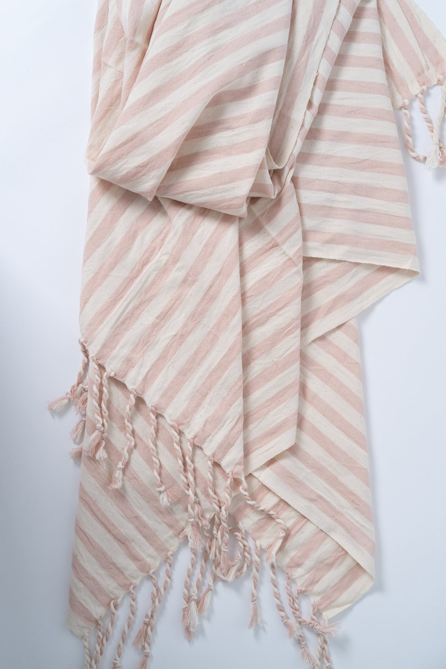 Striped pink and white towel with tassels on a light gray background
