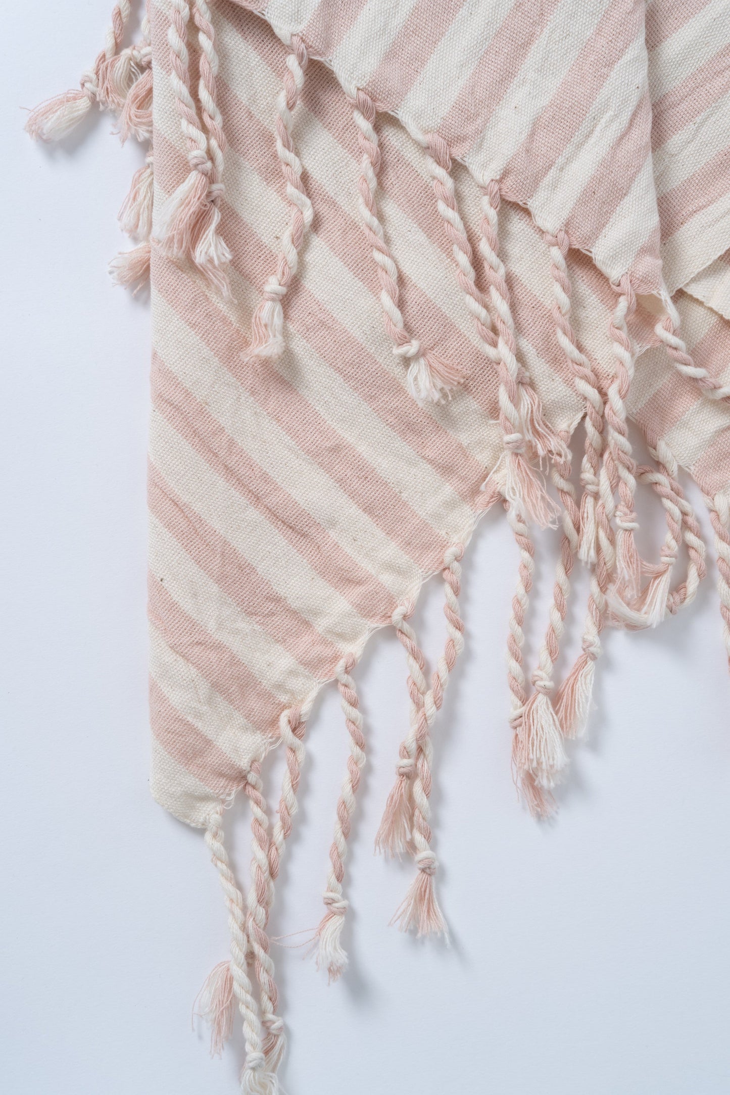 Textile with pink and white stripes and tassels on a light gray background