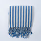Blue and white striped towel with fringes on a light gray background