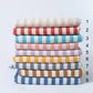 Stack of colorful striped towels with a measurement scale on a light gray background