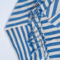 Blue and white striped towel with tassels on a light gray background