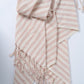 Striped pink and white towel with tassels on a light gray background