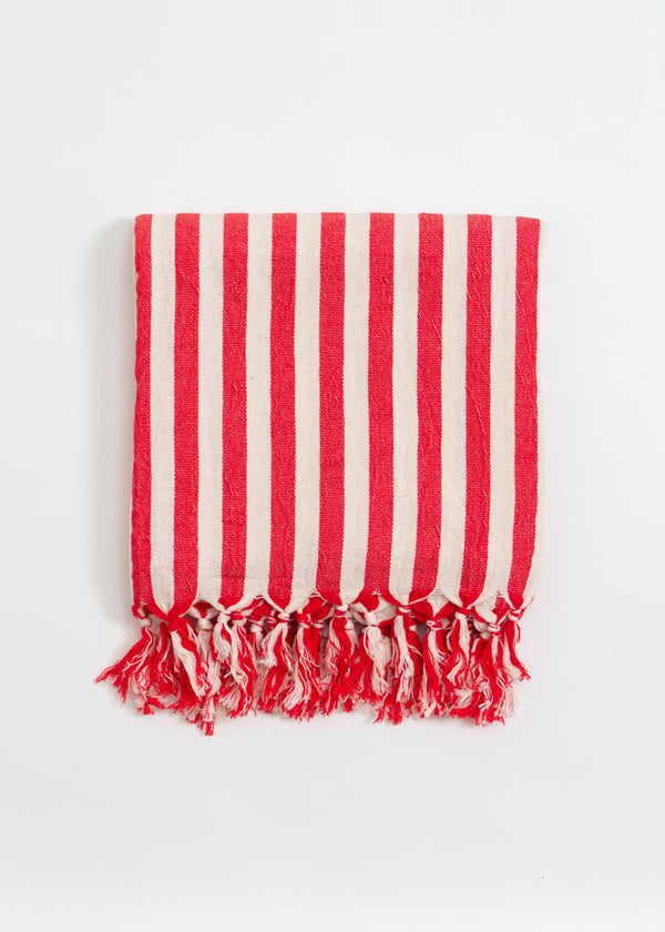 Red and white striped towel with fringes on a light gray background
